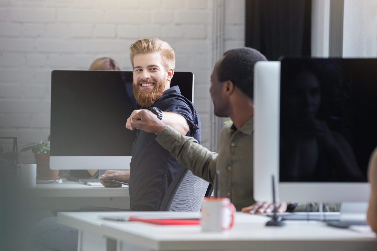 Smiling bearded man giving a fist bump to a male colleague